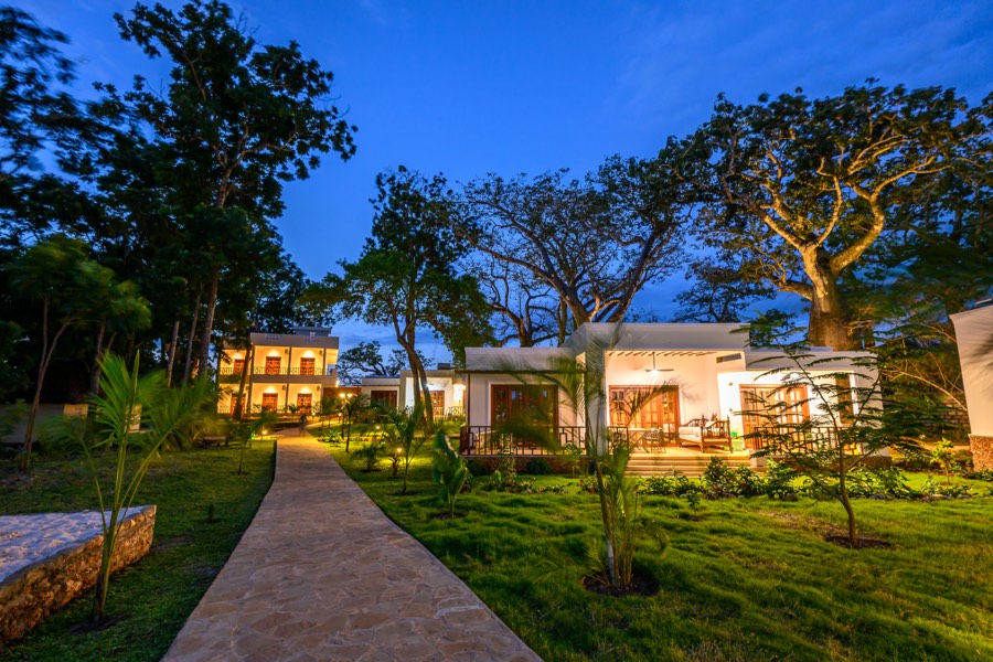 Kasa Pomboo guest cottages lit up at dusk along a garden path