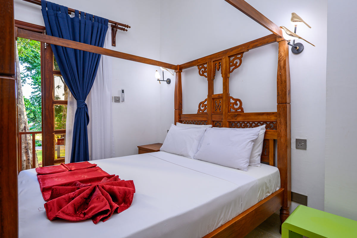 Carved four-poster bed with ocean-view balcony in a Kasa Pomboo guest room