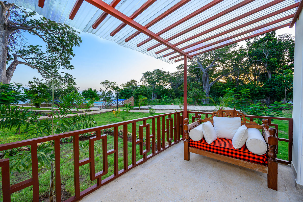 Private veranda daybed at the Family Cottage overlooking the garden and pool at dusk