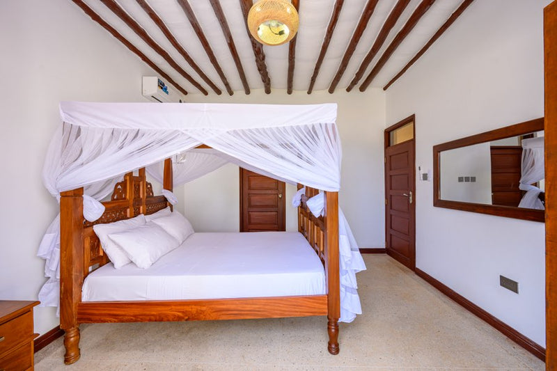 Four-poster bed with mosquito net in a Kasa Pomboo guest room