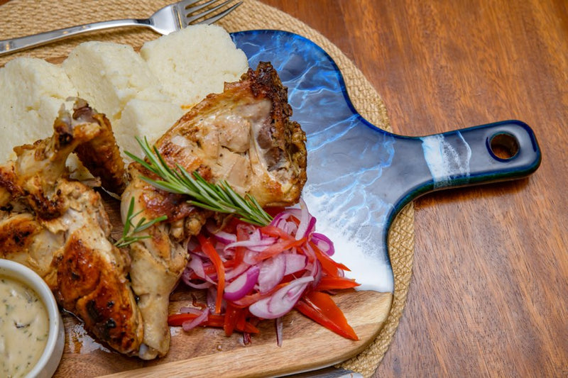 Plated grilled chicken with ugali and kachumbari salad